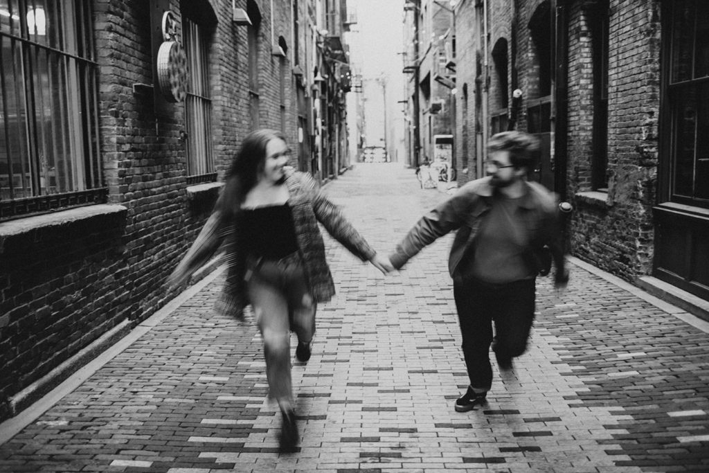 couples session in seattle, wa. Couple runs hand in hand down cobblestone street