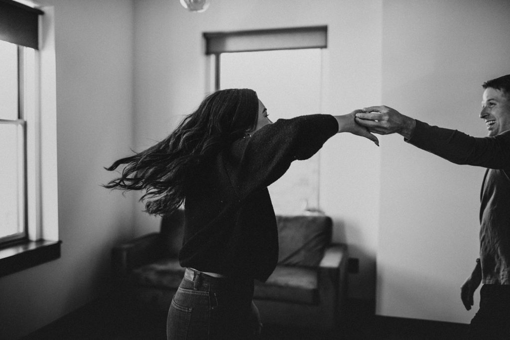 couple dancing during studio session. Photo in black and white and shows couple holding hands while woman twirls and man smiles