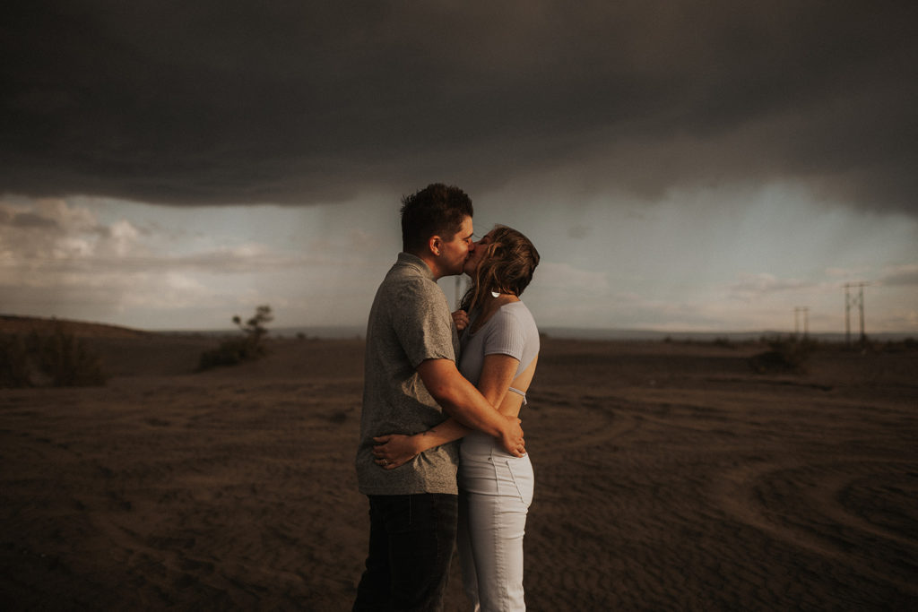 sand dunes engagement photos with stormy skies in the background