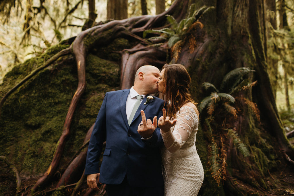 rain forest elopement bride and groom kissing and showing off wedding rings