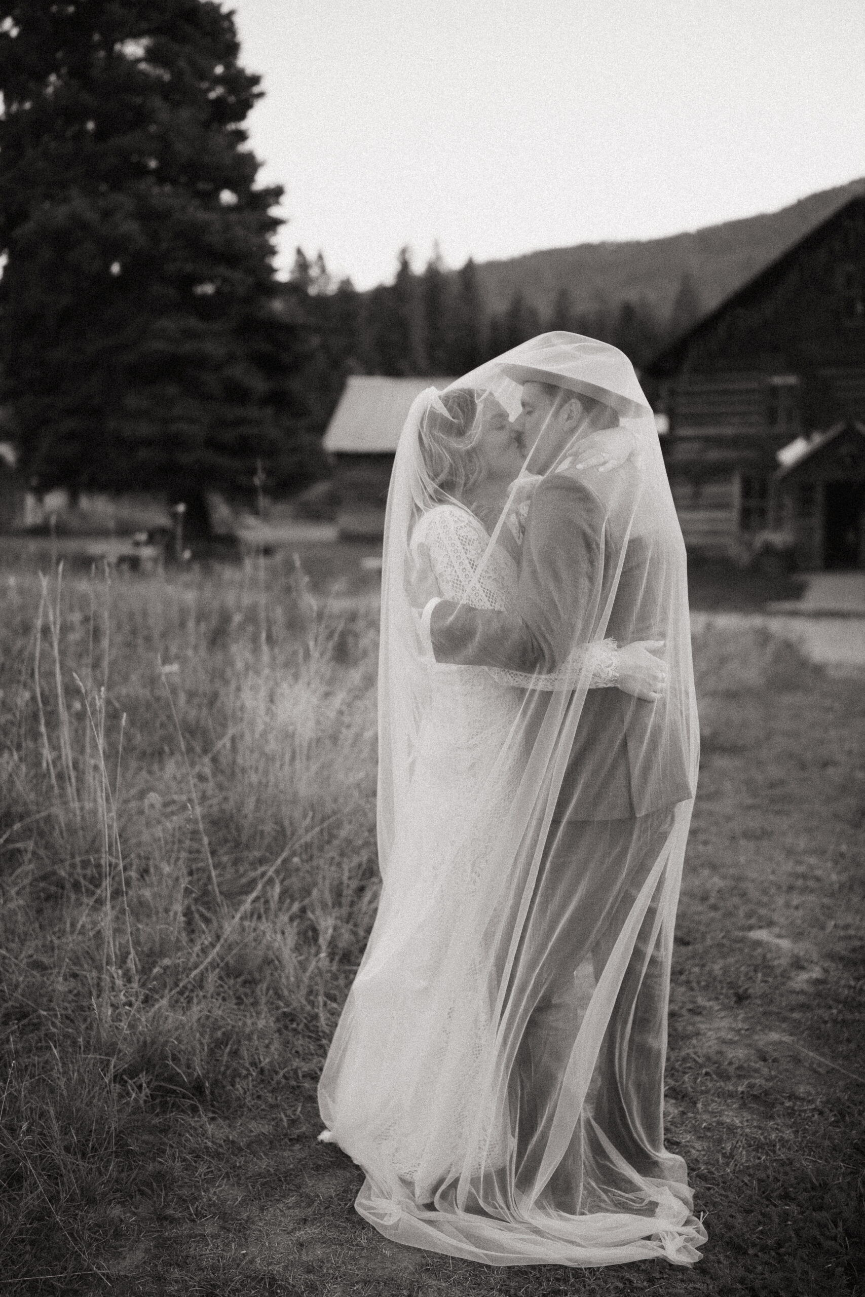 Couple kissing under veil on wedding day