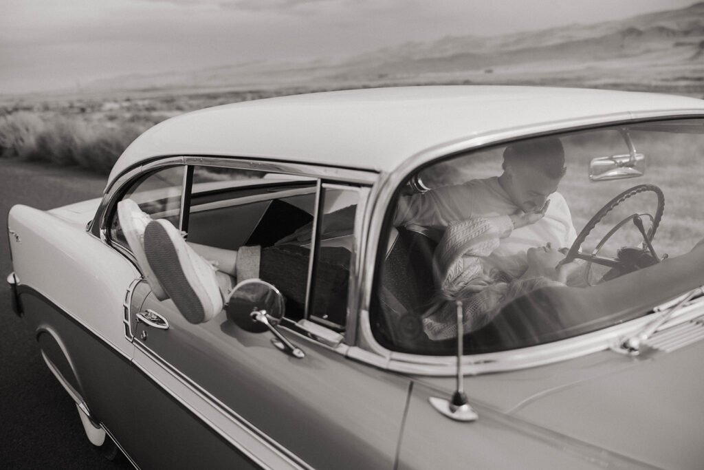 Couple laying in the front seat of a vintage car during Royal city engagement session portrait.