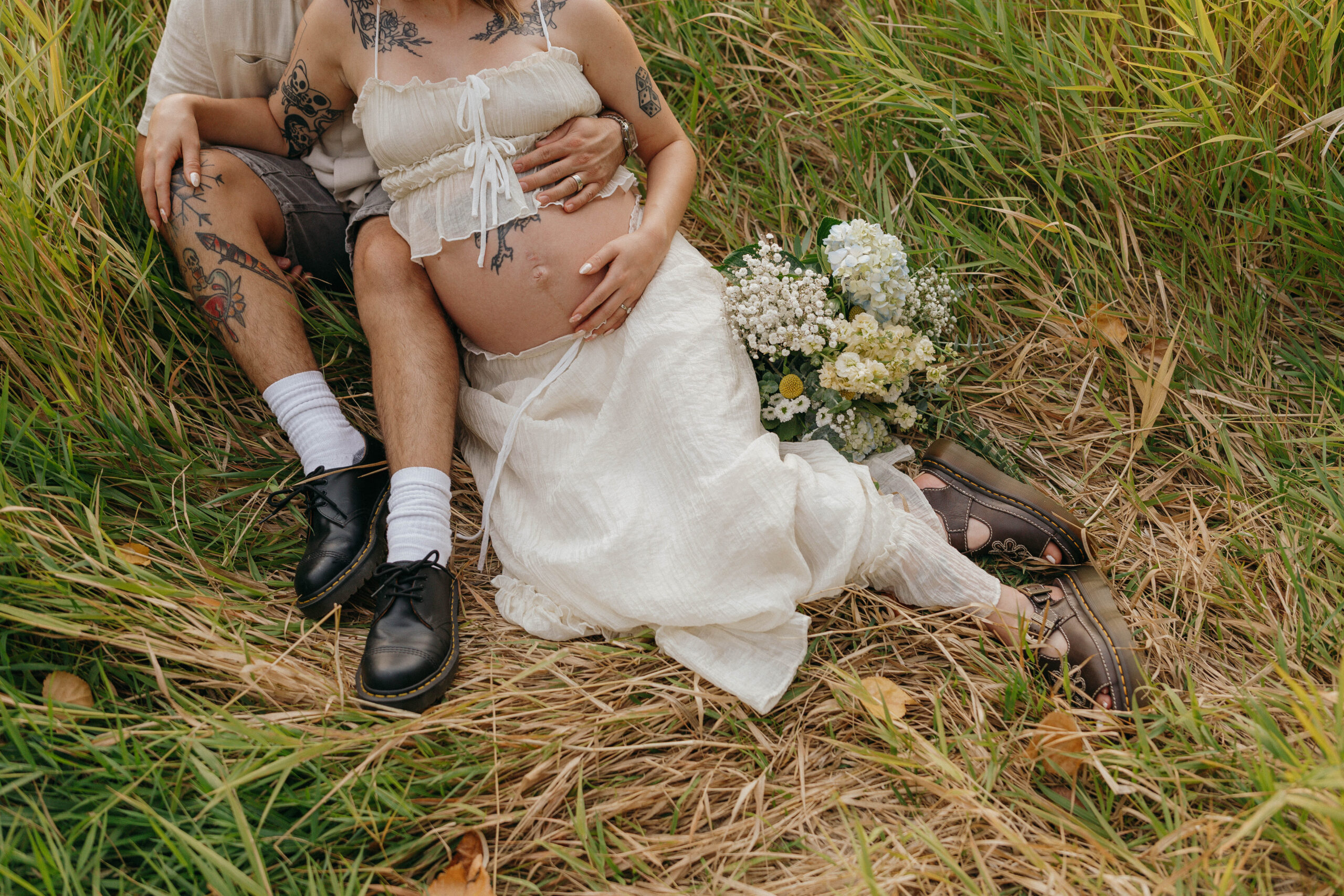 couple in field celebrating pregnancy at dreamy golden hour
